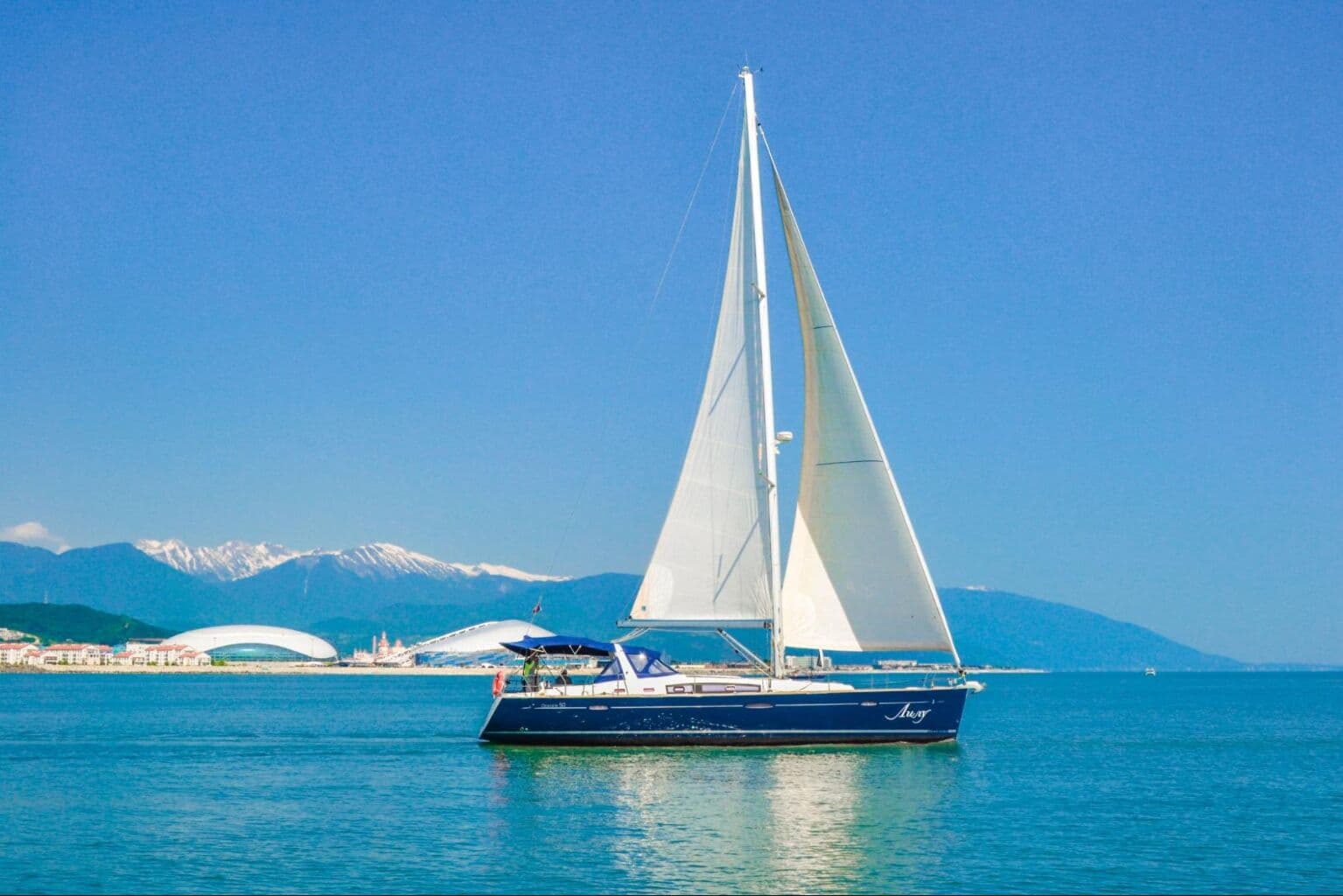 Красивое парусное судно в Черном море на фоне олимпийских объектов